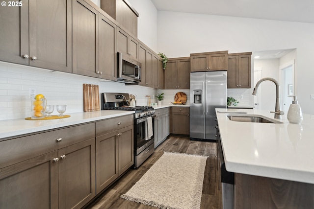 kitchen featuring dark wood-type flooring, stainless steel appliances, light countertops, and a sink