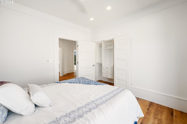 bedroom with recessed lighting, wood finished floors, and a closet
