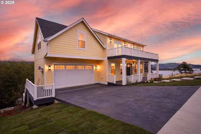 view of front facade with a garage, a balcony, concrete driveway, a porch, and a front yard