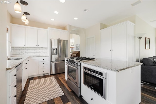 kitchen with a kitchen island, stainless steel appliances, light stone countertops, and a sink
