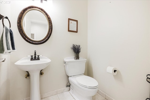 half bath with baseboards, tile patterned floors, and toilet