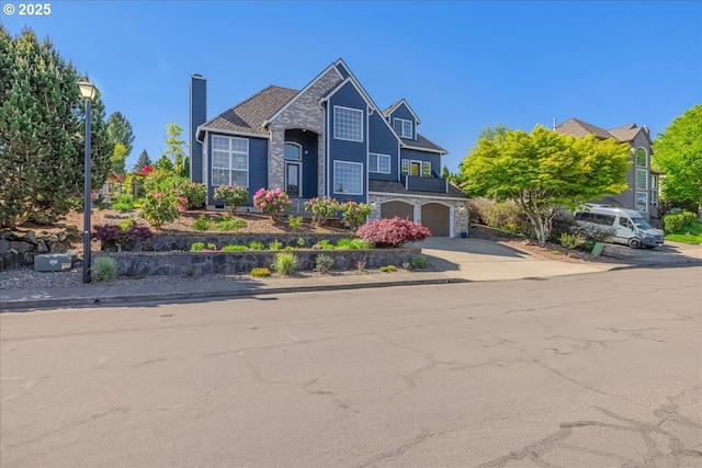 traditional-style home with a garage, a chimney, driveway, and stone siding