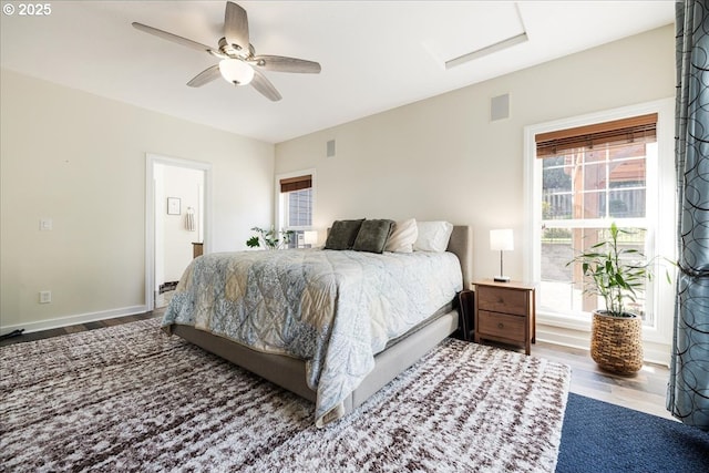 bedroom with a ceiling fan, attic access, visible vents, wood finished floors, and ensuite bathroom