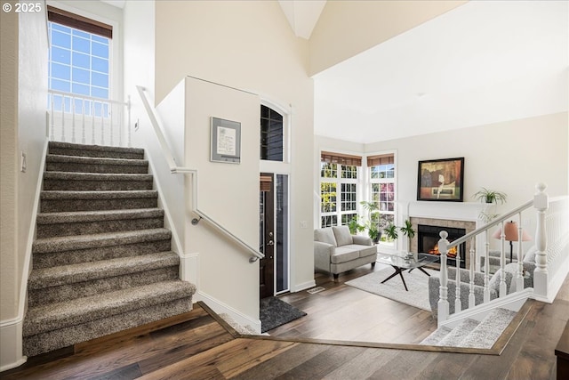 stairway with a warm lit fireplace, baseboards, and wood finished floors
