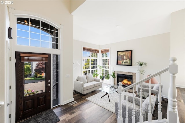 entryway featuring baseboards, dark wood finished floors, a glass covered fireplace, and visible vents