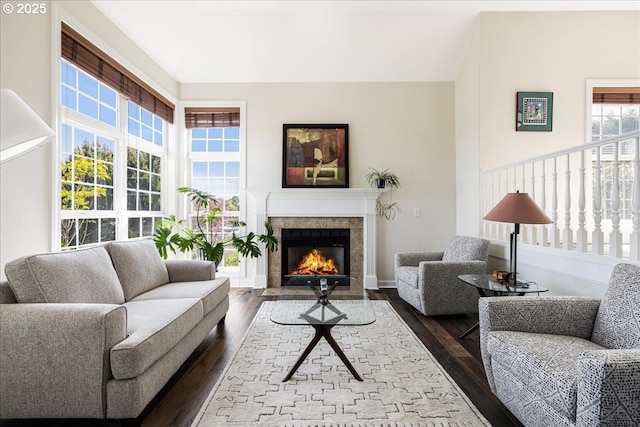 living area featuring a tiled fireplace and dark wood-style flooring