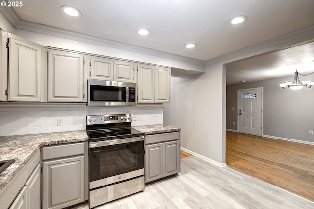 kitchen with light wood finished floors, tasteful backsplash, stainless steel appliances, and crown molding