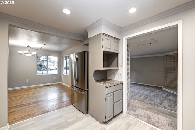 kitchen featuring a notable chandelier, ornamental molding, light wood-type flooring, gray cabinets, and freestanding refrigerator