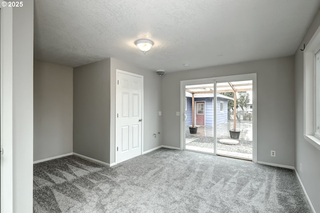 carpeted spare room featuring baseboards and a textured ceiling