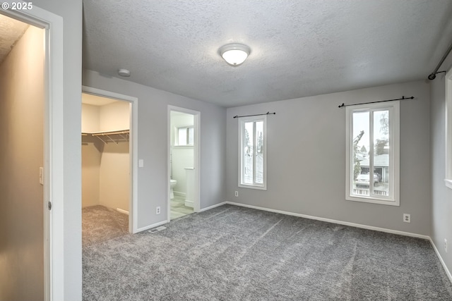 unfurnished bedroom with baseboards, visible vents, a walk in closet, carpet flooring, and a closet