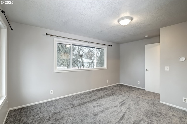 carpeted empty room featuring a textured ceiling and baseboards