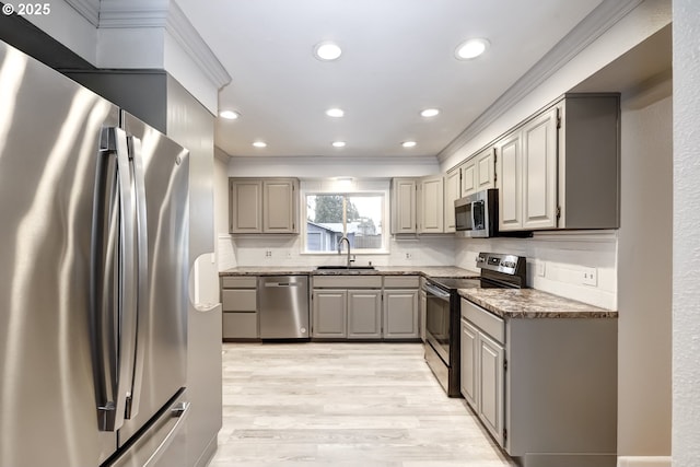 kitchen featuring appliances with stainless steel finishes, a sink, backsplash, and gray cabinetry