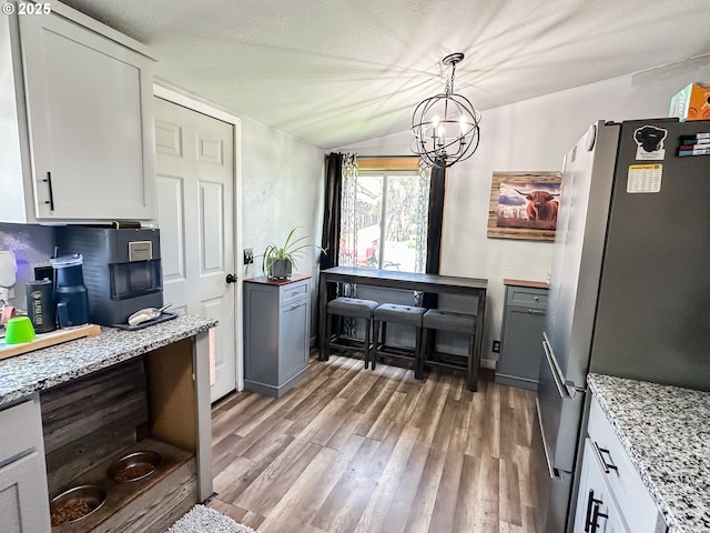 1315 Auburn Ave, Baker City, OR 97814 - kitchen featuring freestanding refrigerator, light wood-type flooring, a chandelier, light stone counters, and lofted ceiling