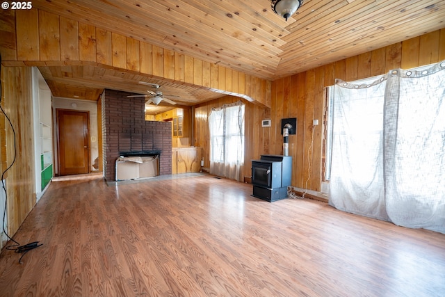 unfurnished living room with wood finished floors, a wood stove, a brick fireplace, and wood ceiling