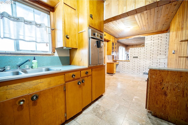 kitchen featuring brick wall, oven, wood ceiling, light countertops, and a sink