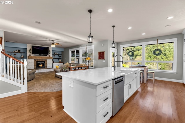 kitchen with dishwasher, a sink, white cabinetry, and light wood-style floors