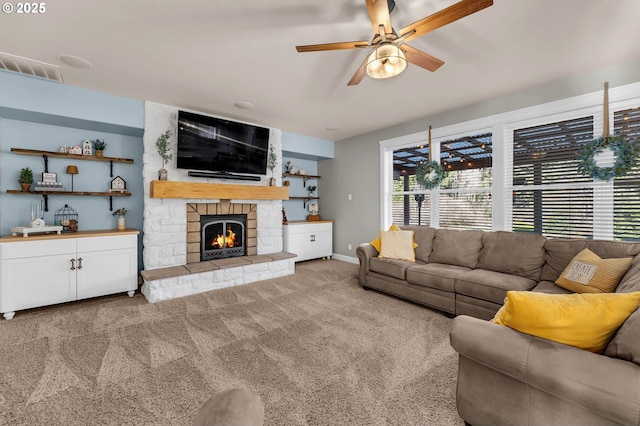 carpeted living area with visible vents, ceiling fan, a stone fireplace, and baseboards