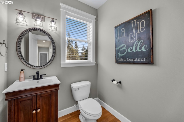 bathroom with toilet, baseboards, wood finished floors, and vanity