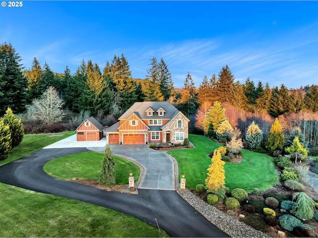 view of front of house featuring aphalt driveway, a front lawn, an attached garage, and a view of trees