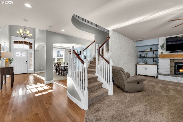 entryway with a fireplace, baseboards, stairway, hardwood / wood-style floors, and an inviting chandelier