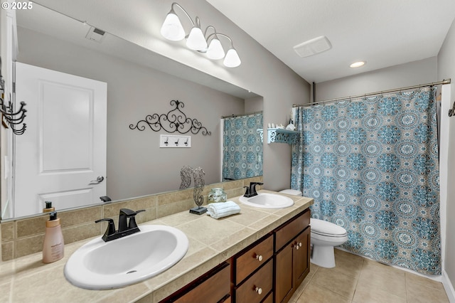 bathroom featuring double vanity, a sink, toilet, and tile patterned floors