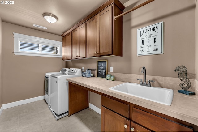 washroom featuring cabinet space, visible vents, light tile patterned flooring, a sink, and separate washer and dryer