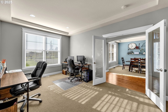 office space featuring a tray ceiling, french doors, baseboards, and wood finished floors