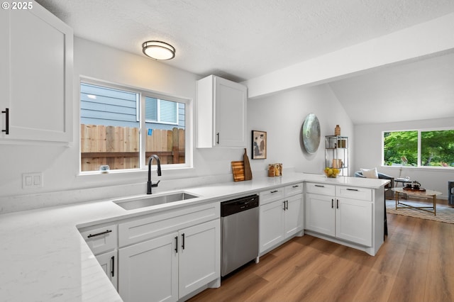 6300 SW Arranmore Pl, Portland, OR 97223 - kitchen with stainless steel dishwasher, a peninsula, light wood-style flooring, white cabinetry, and lofted ceiling