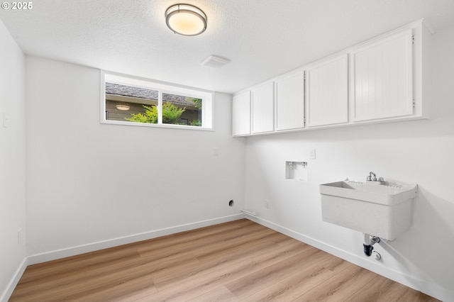 6300 SW Arranmore Pl, Portland, OR 97223 - laundry area featuring cabinet space, light wood-type flooring, washer hookup, and a textured ceiling