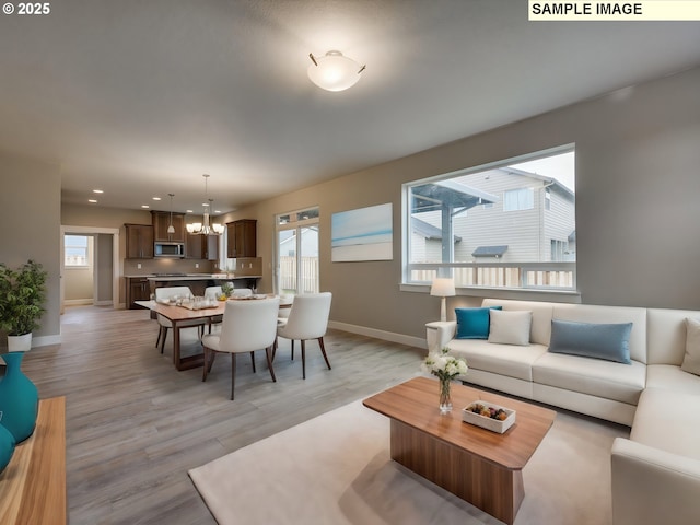 living area featuring baseboards, recessed lighting, light wood-style flooring, and a chandelier