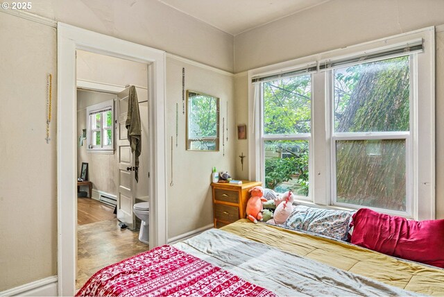 bedroom featuring baseboards, ensuite bath, and a baseboard radiator