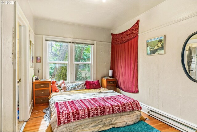 bedroom with wood finished floors and baseboard heating