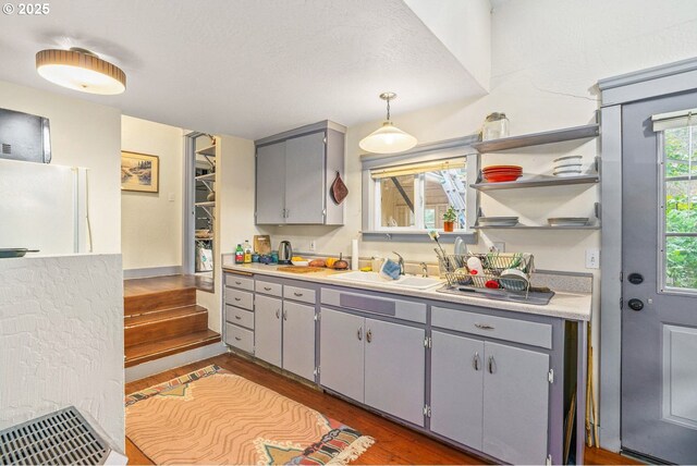 kitchen with gray cabinets, light countertops, a sink, freestanding refrigerator, and wood finished floors
