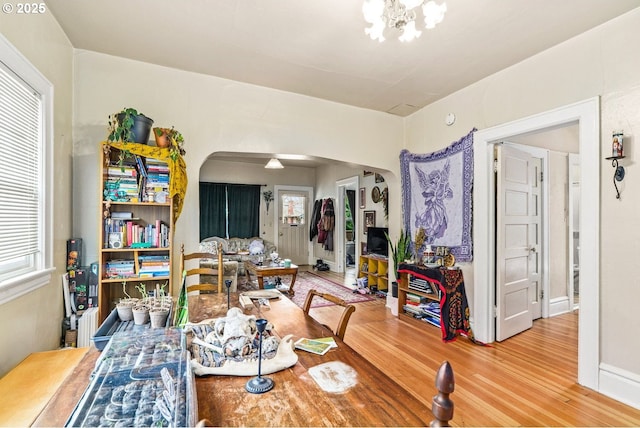 dining area featuring arched walkways, wood finished floors, and a notable chandelier