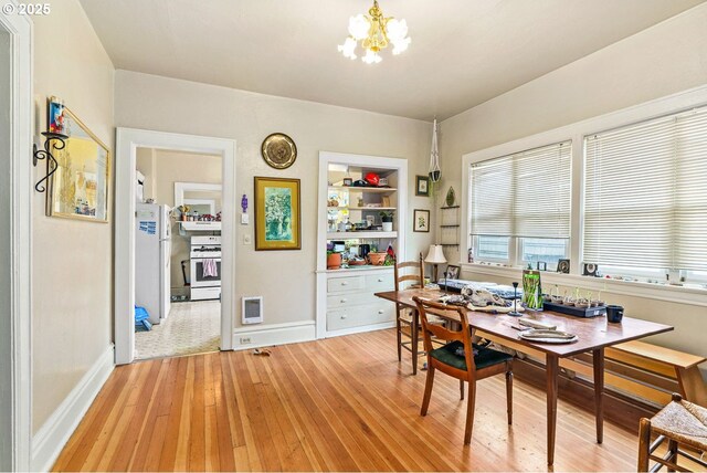 dining area featuring a chandelier, light wood-type flooring, built in features, baseboards, and visible vents