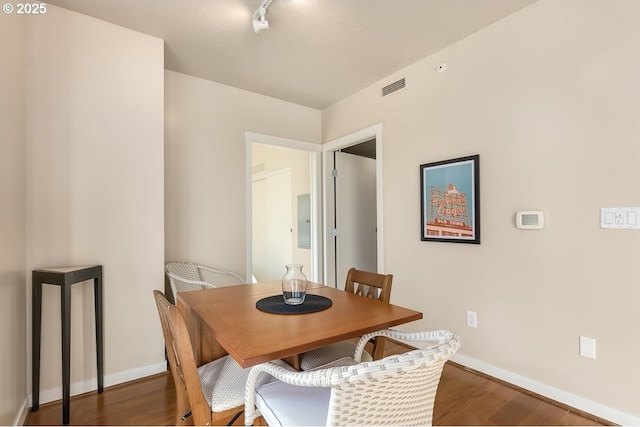 dining room featuring rail lighting, electric panel, and dark hardwood / wood-style floors