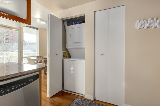 clothes washing area with stacked washer / drying machine and light hardwood / wood-style floors