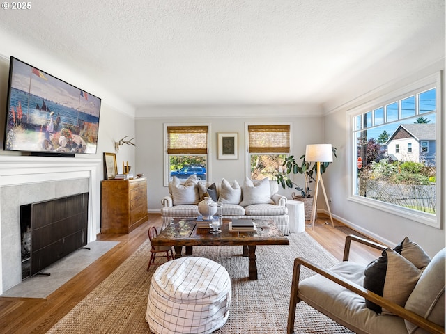 3556 NE Alberta Ct, Portland, OR 97211 - living area featuring wood finished floors, a tiled fireplace, a textured ceiling, and baseboards