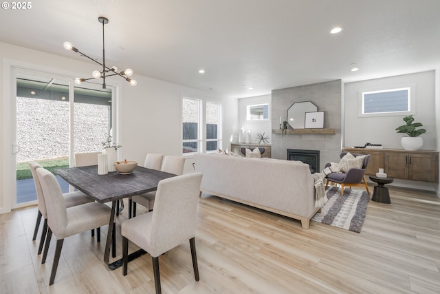143 W 20th Way, La Center, WA 98629 - dining area with light wood-style flooring, a tiled fireplace, a chandelier, and recessed lighting