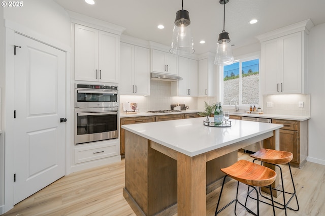 143 W 20th Way, La Center, WA 98629 - kitchen featuring under cabinet range hood, stainless steel appliances, light wood-style floors, recessed lighting, and backsplash