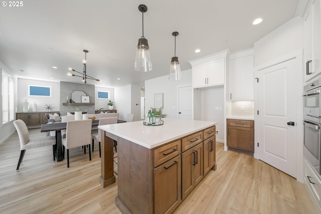143 W 20th Way, La Center, WA 98629 - kitchen with white cabinets, brown cabinetry, light wood-type flooring, a center island, and recessed lighting