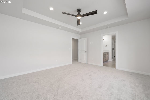 143 W 20th Way, La Center, WA 98629 - unfurnished bedroom featuring a tray ceiling, recessed lighting, light colored carpet, connected bathroom, and ceiling fan