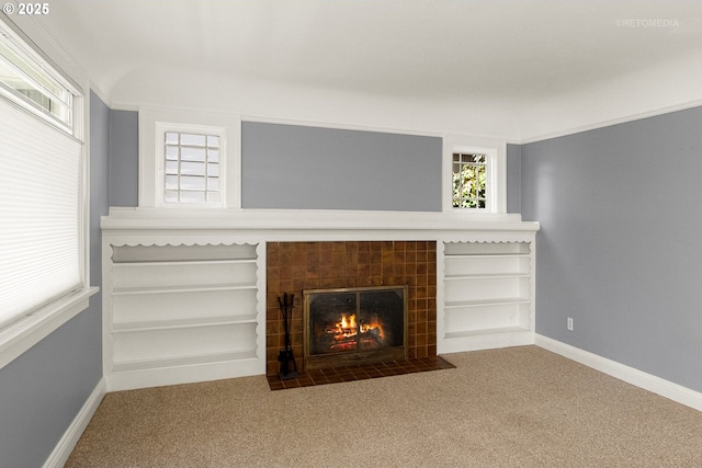 unfurnished living room with ornamental molding, carpet flooring, and a tile fireplace