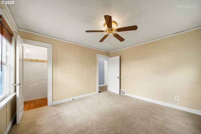 unfurnished bedroom with crown molding, a closet, ceiling fan, and carpet