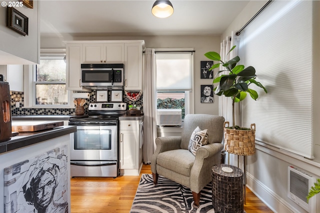 kitchen with white cabinetry, stainless steel appliances, light hardwood / wood-style flooring, and backsplash