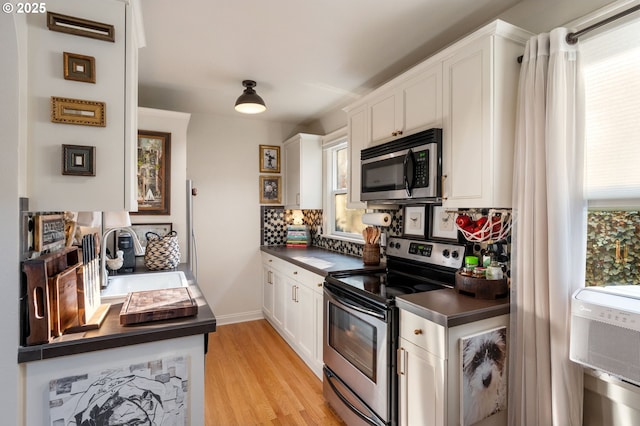 kitchen with stainless steel appliances, backsplash, white cabinets, and light wood-type flooring