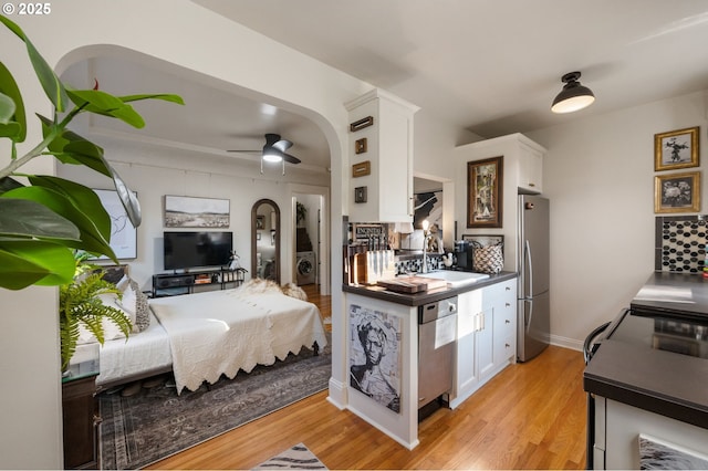 kitchen with stainless steel appliances, washer / dryer, white cabinets, and light wood-type flooring