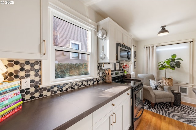 kitchen featuring appliances with stainless steel finishes, white cabinetry, backsplash, tile counters, and light wood-type flooring