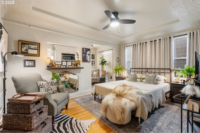 bedroom featuring a raised ceiling, wood-type flooring, and a textured ceiling