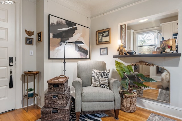 sitting room with ornamental molding and hardwood / wood-style floors